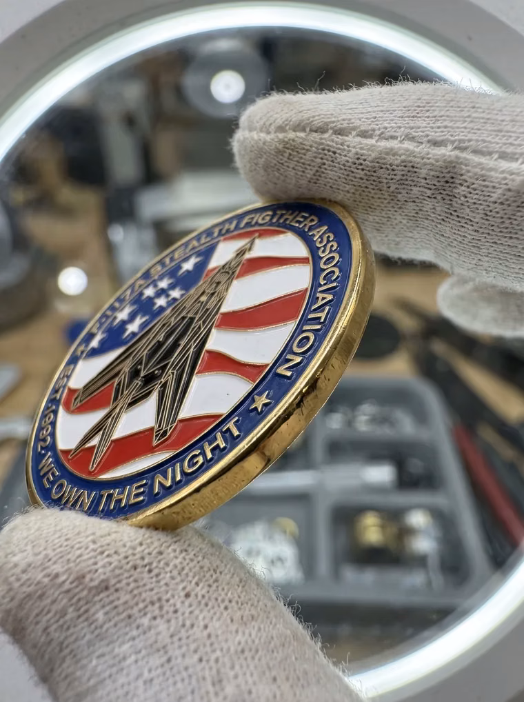 A finished firefighter association coin held up in white cotton gloves for inspection