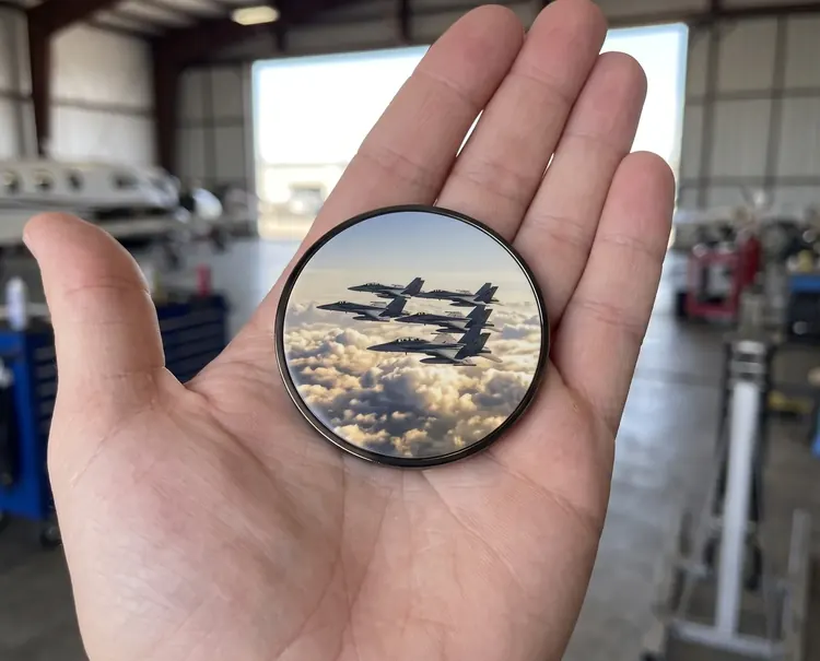 A classic Quick UV coin with a black nickel rim and a fighter jet print, held in a palm
