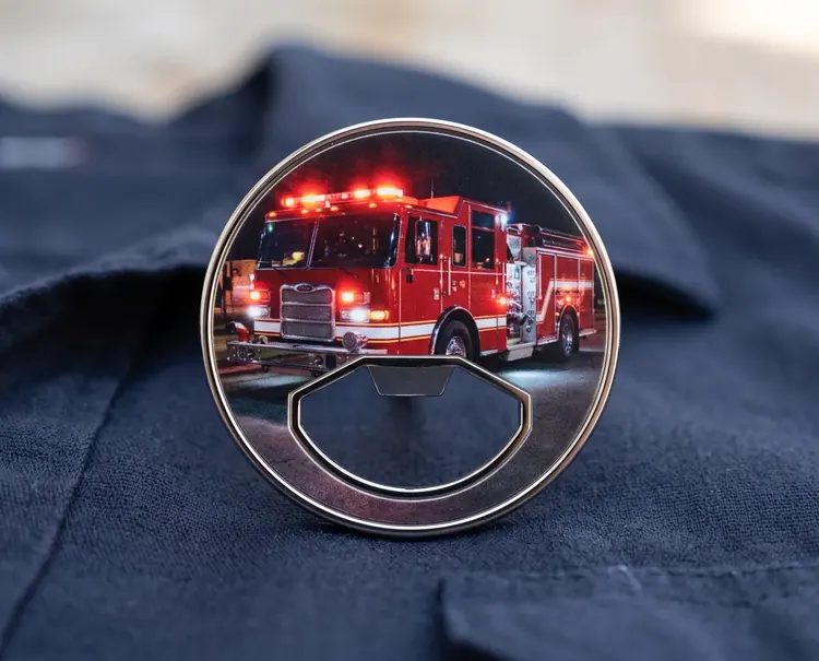 A bottle opener Quick UV coin with a polished nickel rim and a fire engine print