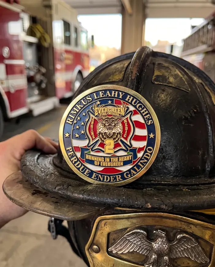 An Evergreen Fire Rescue coin held against a leather fire helmet in the station